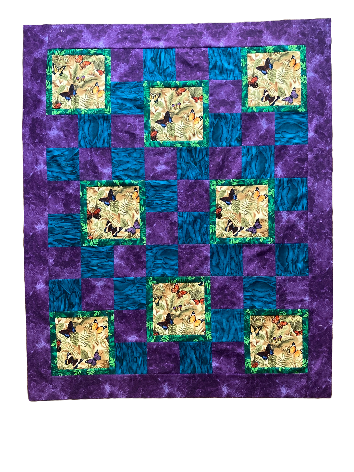 Portrait mode quilt in teal and purple with butterflies.